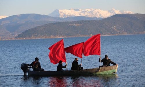 Ξαναζωντάνεψαν στη λίμνη Παμβώτιδα «Οι κυνηγοί» του Θόδωρου Αγγελόπουλου με βάρκες και κόκκινες σημαίες (Βίντεο)